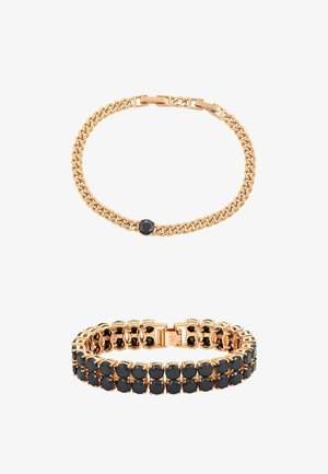 Twee gouden armbanden: één met een enkele zwarte steen aan een ketting, de ander met meerdere zwarte stenen in een dubbele rij gezet.