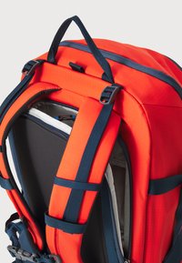 Mochila roja y azul marino con correas acolchadas, tela texturizada, asa superior y compartimento con cremallera. Incluye correas ajustables.