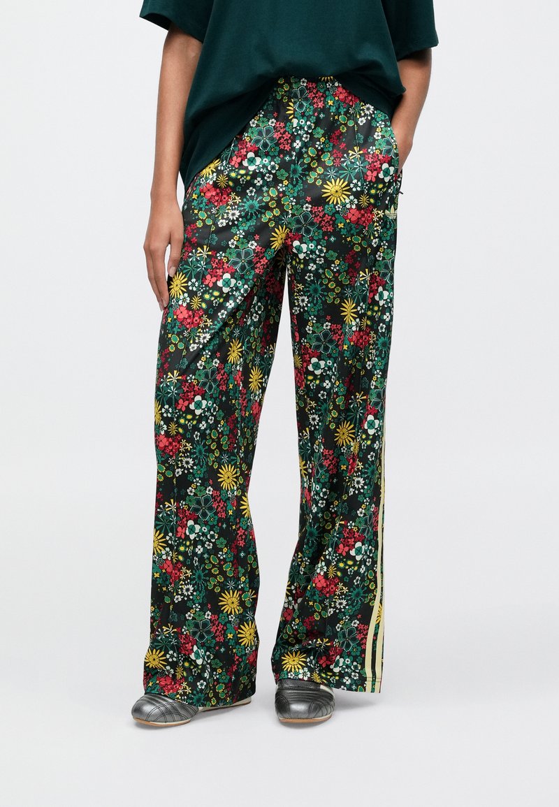 Flowing dark green floral pants with a vibrant pattern of red, yellow, and white flowers, featuring a wide-leg design and side stripes.