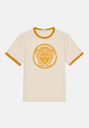 Kremowy t-shirt z krótkim rękawem, z musztardowo-żółtym wykończeniem na kołnierzyku i rękawach, z dużą musztardowo-żółtą grafiką głowy Meduzy z przodu.