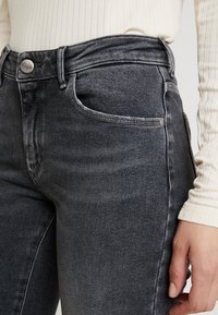Grå denimjeans med hög midja, med knappstängning, framfickor och minimalistisk design. Mjuk textur och lätt blekning.