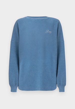 Langærmet lyseblå strikket trøje med rund hals og lille hvidt broderet tekst på øverste venstre bryst.