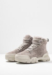 Harmaat mokkapintaiset puolikengät, joissa on tekstuuripinta, vaaleat kumipohjat ja nauhat. Pehmeä vuori kauluksessa lisää mukavuutta.