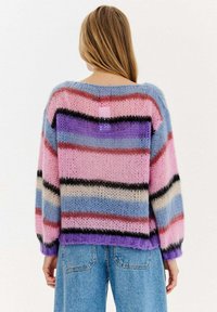 Pletený svetr s vícebarevnými pruhy v růžové, modré, černé a krémové barvě. Volný střih s širokými rukávy a kulatým výstřihem.