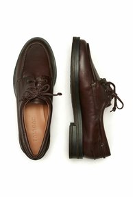 Paire de chaussures habillées en cuir brun foncé à lacets, l’une vue de dessus et l’autre de côté, avec des semelles noires.