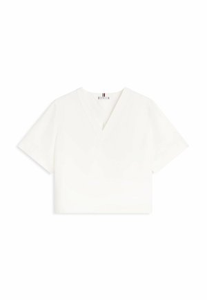 Camiseta blanca recortada con mangas cortas y escote en V, mostrada sobre un fondo blanco liso.