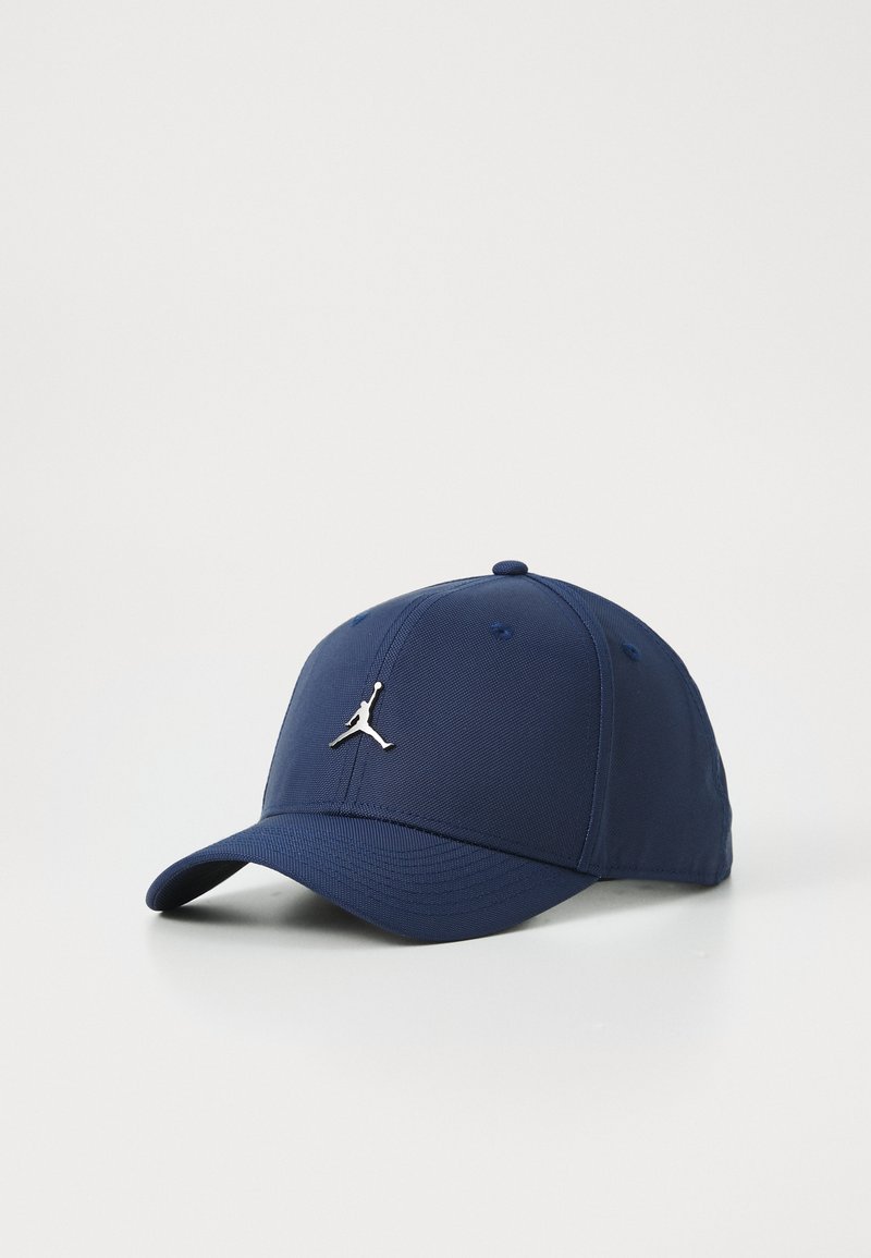 Marineblå baseball cap med en buet skygge, der har et sølvfarvet Jumpman-logo på forsiden og et tekstureret stofdesign.