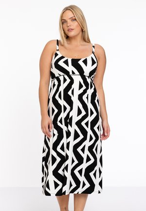Robe maxi à motif noir et blanc avec un design sans manches, un décolleté carré et une taille ajustée. Le tissu semble lisse et léger.