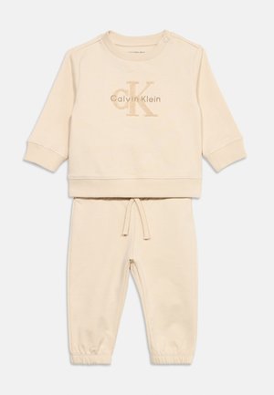 Beež Calvin Kleini beebide komplekt, mis sisaldab pika varrukaga dressipluusi logoga ja sobiva lõikega elastse vöökohaga pükse nööriga.