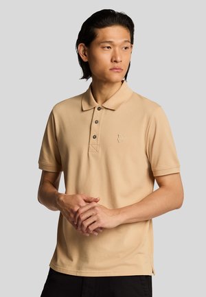 Polo a maniche corte beige in cotone, con colletto classico, patta con tre bottoni e logo ricamato discreto sul petto.