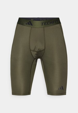 Oliņu zaļas kompresijas bikses ar melnu TECHFIT jostu, ar gludu tekstūru, pieguļošu formu un smalkiem šuvju elementiem.