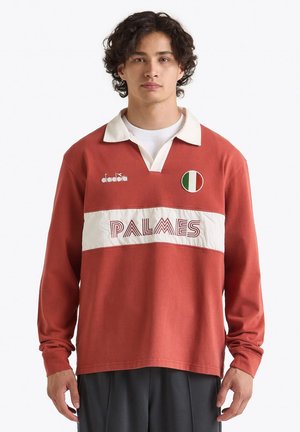 Maglietta da rugby a maniche lunghe rossa con pannello orizzontale bianco, presenta la scritta "PALMES" e un'emblema della bandiera italiana. Realizzata in cotone con un design con colletto.