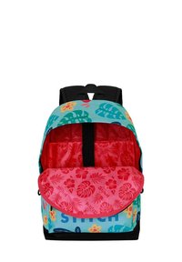 Mochila multicolor con un diseño floral tropical, exterior en color verde azulado, interior rojo y correas negras. Presenta una solapa y un logo en la parte frontal.