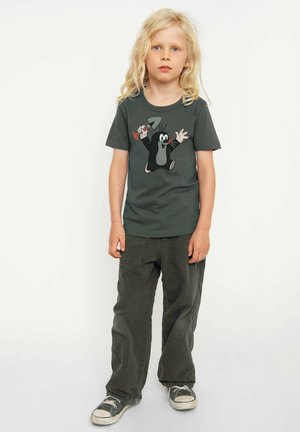 Dark green cotton t-shirt features a cartoon mole holding a shovel, paired with loose, olive green pants and black canvas sneakers.
