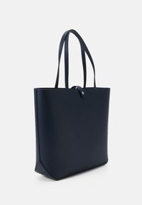 Marinblå tygväska i slätt material, med två robusta handtag och en minimalistisk design med ett tryckknappslås.