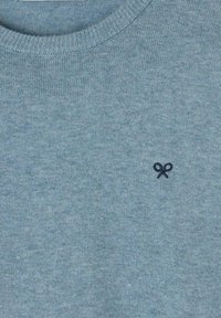 Suéter azul claro con cuello redondo acanalado y un pequeño logo de tijeras en navy bordado en el pecho. Textura de punto suave.