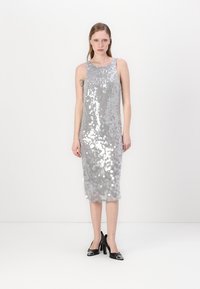 Vestido prateado com brilhantes, de silhueta ajustada, comprimento até ao joelho e design sem mangas; textura suave com detalhes refletivos.