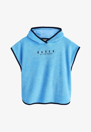 Uśmiechnięty chłopiec o kręconych włosach, ubraną jasnoniebieski ręcznik z kapturem z napisem „Baker by Ted Baker” z przodu na jednolitym tle.