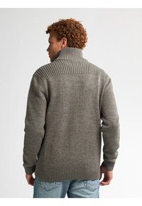 Grau gestrickter Pullover mit hohem geripptem Kragen, texturierten Schultern und gerippten Bündchen, aus einem weichen, warmen Material.