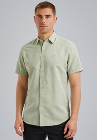 Korte mouwen, lichtgroene blouse met een gestructureerde stof, subtiel logo op de borst en een gebogen zoom.