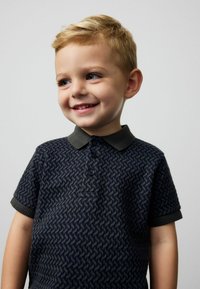 Polo navy con motivo testurizzato, maniche corte e colletto verde scuro. Chiusura a tre bottoni e dettagli ricamati.