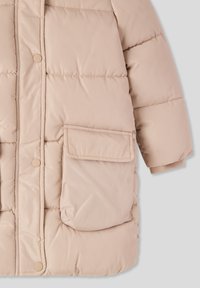 Beżowa ocieplana kurtka z przodem na napy, dużą kieszenią z boku oraz ściągaczami przy mankietach dla lepszego dopasowania.