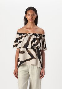 Olkapäältä avattu yläosa, jossa on kerroksellinen, röyhelöinen muotoilu. Materiaali on beige ja siinä on abstrakteja ruskeita ja mustia kuvioita. Pehmeä ja kevyt kangas.