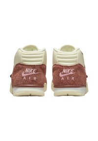 Nike Air tennarit, joissa on vaalean kermanvärinen nahka yläosa, vaaleanpunainen mokka kantapään osa, teksturoitu takapinta ja vaaleanpunainen logo yksityiskohta. Pyöreä muoto, jossa pehmustettu kaulus.