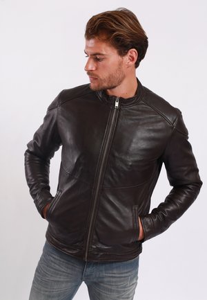 Chaqueta de cuero marrón con cuello alzado, cremallera frontal y bolsillos laterales. Presenta un diseño elegante y una textura suave.