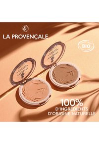 Deux compacts ronds de bronzer avec des motifs de feuilles en relief. Celui de gauche est marron clair ; celui de droite est plus foncé. Couvercles transparents avec des bases blanches.