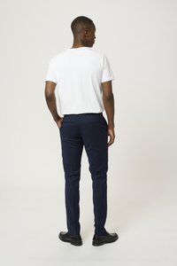 Camiseta blanca, pantalones de vestir azul marino y zapatos negros. Diseño simple con forma ajustada, estilo de pierna recta y sin patrones ni acentos visibles.