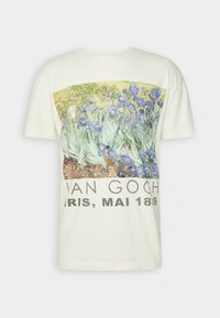 Kermansävyinen puuvillainen t-paita, jossa värikäs Van Goghin kurjenmiekka-taideteos ja alhaalla paksulla mustalla tekstillä "VAN GOGH PARIS, MAI 1889".