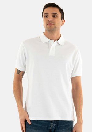 Witte polo shirt van katoen, met een kraag, een sluiting met twee knopen en korte mouwen, gedragen met donkerblauwe jeans.