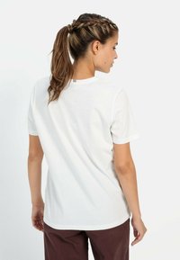 Hvid bomulds t-shirt med korte ærmer, rund hals og en subtil stribet detalje på ryggen. Glat tekstur og afslappet pasform.
