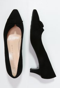 Chaussures à talons aiguilles en daim noir avec un bout pointu et un nœud décoratif à l'avant. Présentent un talon bloc texturé et une semelle intérieure lisse.