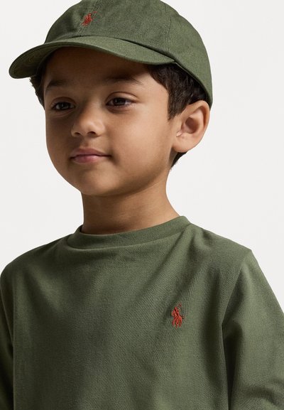 Zöld pamut póló, kerek nyakkal, kis piros polo logóval a mellrészen. Hozzá illő zöld baseball sapka állítható pánttal.