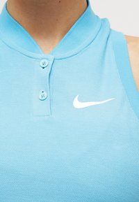 Polo shirt azzurro chiaro realizzato in tessuto testurizzato, con colletto button-down e logo Nike bianco sul lato sinistro.