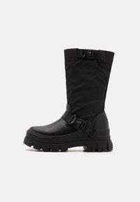 Bottes noires mi-mollet en matériau synthétique, avec une tige texturée, une sangle à boucle et une semelle en caoutchouc épaisse à profonde adhérence.