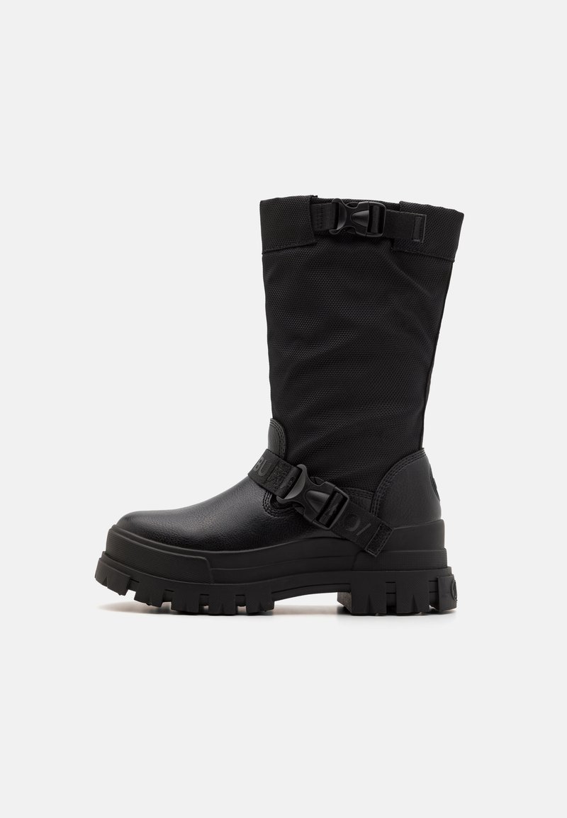 Bottes noires mi-mollet en matériau synthétique, avec une tige texturée, une sangle à boucle et une semelle en caoutchouc épaisse à profonde adhérence.
