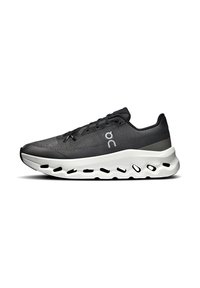Scarpa sportiva nera con parte superiore testurizzata, design con lacci e suola bianca imbottita con fori per la traspirabilità.