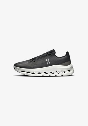 Scarpa sportiva nera con parte superiore testurizzata, design con lacci e suola bianca imbottita con fori per la traspirabilità.
