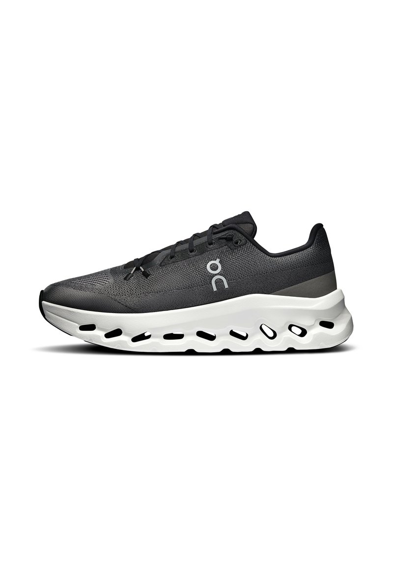 Scarpa sportiva nera con parte superiore testurizzata, design con lacci e suola bianca imbottita con fori per la traspirabilità.