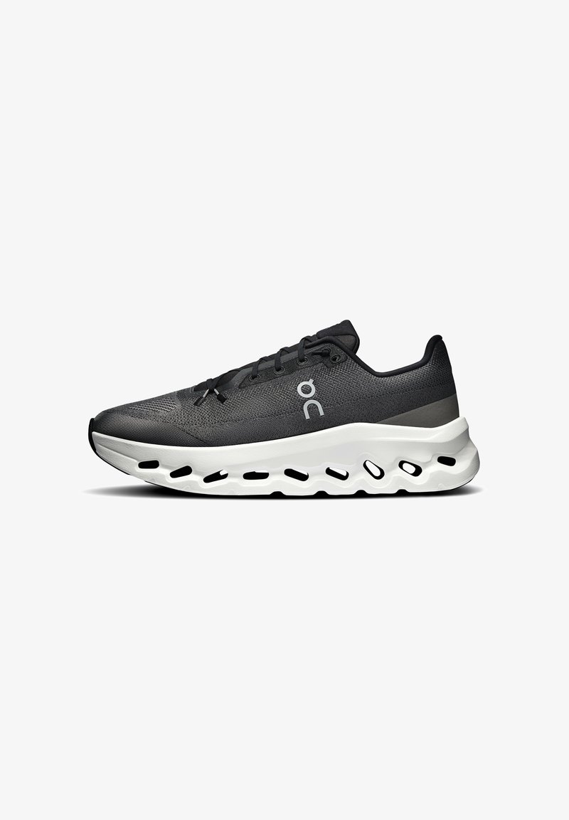 Scarpa sportiva nera con parte superiore testurizzata, design con lacci e suola bianca imbottita con fori per la traspirabilità.
