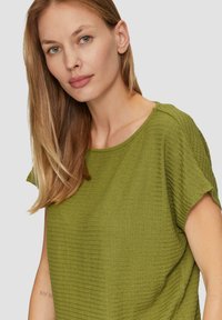Groene gestructureerde top met korte mouwen en een ronde halslijn. Heeft subtiele horizontale strepen en een ontspannen pasvorm.