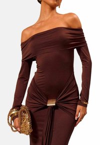 Brun off-the-shoulder kjole lavet af strækstof, med lange ærmer, snoet detalje ved taljen og en gylden accent i midten.