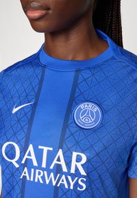 Blå sportströja med geometriskt mönster, rund hals och logotyper: "Qatar Airways" i vitt och "Paris Saint-Germain"-märket.
