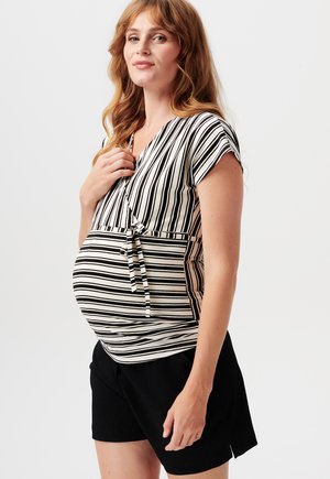 Tehotenský top s vertikálnymi čierno-bielymi pruhmi, krátkymi rukávmi, výstrihom do V a s viazaním v páse, skombinovaný s čiernymi šortkami.