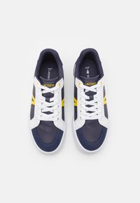 Zapatillas deportivas en azul marino y blanco con acentos amarillos y diseño de cordones; material de cuero liso y textil; puntera redonda y detalle perforado.