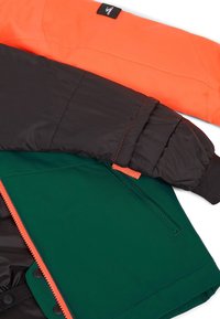 Kleurrijke jas met een zwarte puffy bovenkant, oranje mouwen en een groene onderkant met een oranje rits en drukknoopsluitingen. Gelaagd stof.