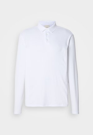 Langermet hvit polo-skjorte laget av mykt stoff, med klassisk krage, treknapps placket og en subtil logo på brystet.